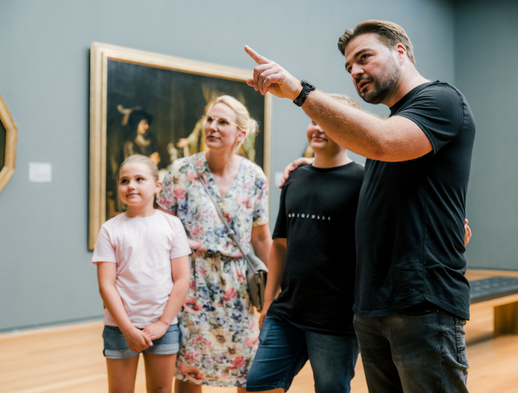 Eine vierköpfige Familie sieht sich zusammen ein Kunstwerk im Museum an