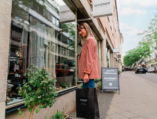 Eine junge Frau schlendert durch die Wolfsschlucht und blickt in ein Schaufenster. 