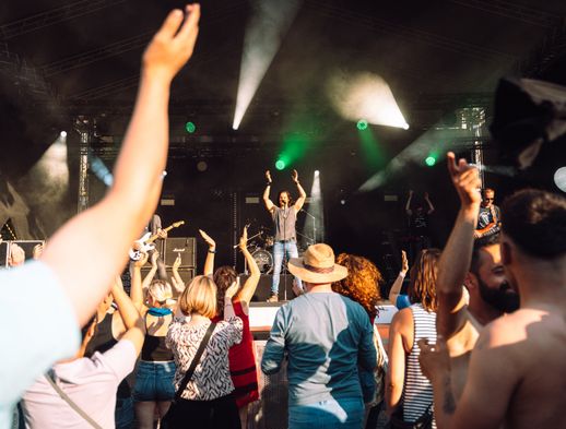 Viele Konzertbesucher jubeln den Musikern auf der Bühne zu. 