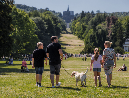 Eine Familie mit Hund läuft im Bergpark Wilhelmshöhe 