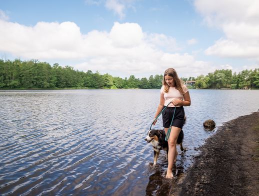 Mädchen läuft mit Hund am Ufer des Sees entlang 