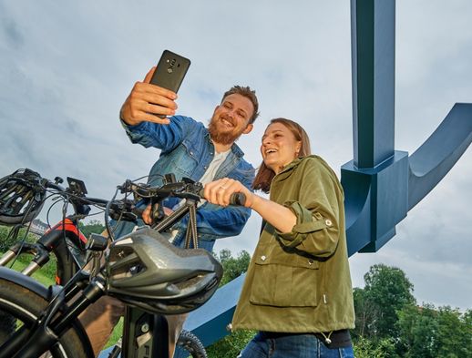 Ein junges Pärchen mach ein Selfie bei einer Radtour vor dem documenta Außenwerk Spitzhacke in Kassel. 