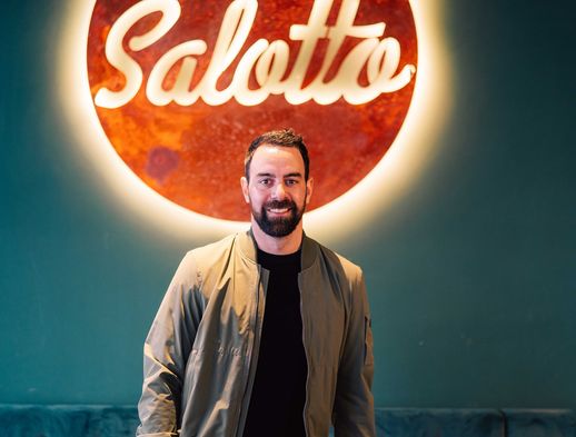 Derek Dinger steht vor dem Logo des Cafes Salotto in der Innenstadt von Kassel. 