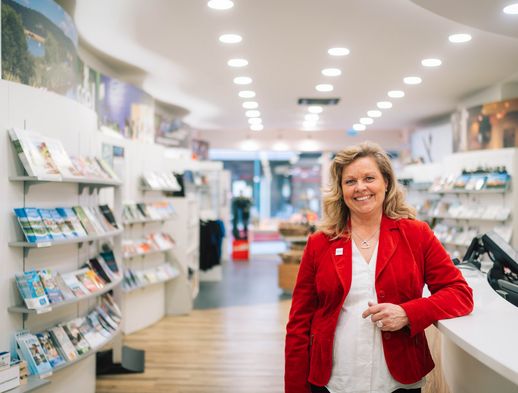 Die freundliche Mitarbeiterin der Tourist Information Kassel Gabriela Thöne lehnt sich an den Verkaufstresen.