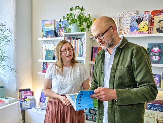 Das Bild zeigt zwei Personen im Rotopol im Quartier Vorderer Westen, die durch ein Magazin blättern. 