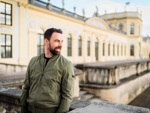 Derek Dinger steht vor der Orangerie in Kassel. 