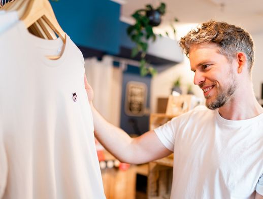 Ein junger Mann schaut sich ein T-Shirt im Conceptstore Stadtliebe an. 