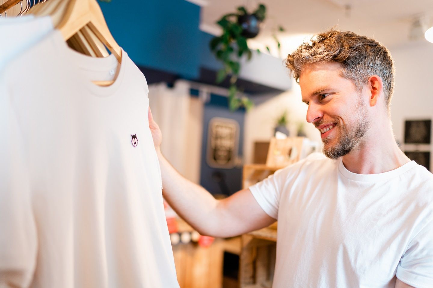 Ein junger Mann schaut sich ein T-Shirt im Conceptstore Stadtliebe an. 